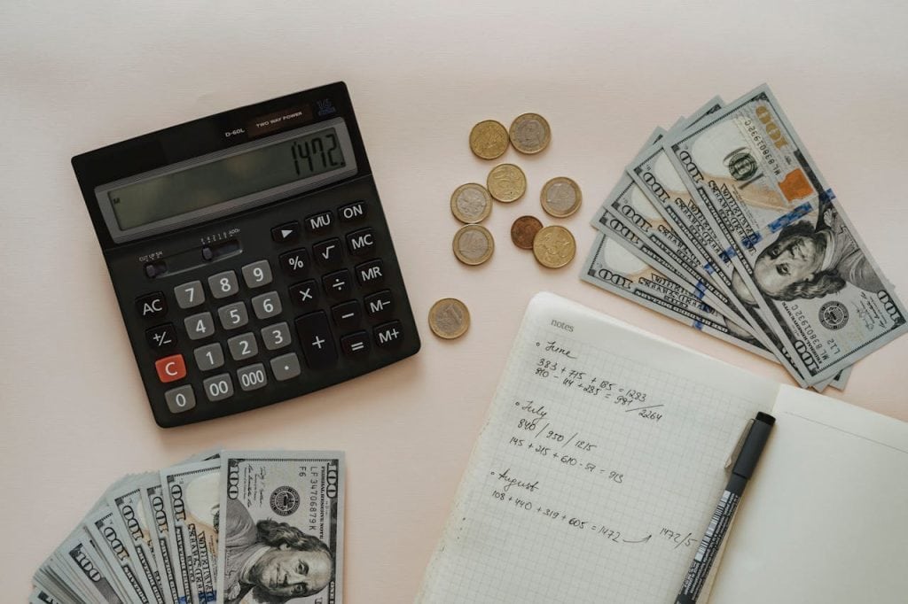 Business financial planning with calculator, cash, and notes for insurance coverage.
