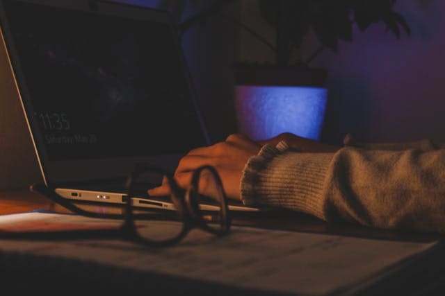 Business professional working on a laptop with risk management documents.